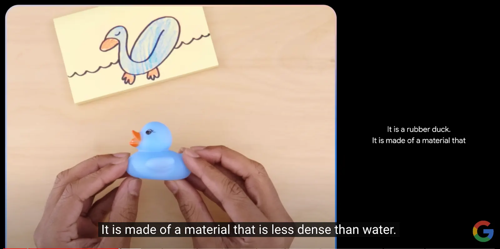 Google video still of hands holding a blue rubber duck beside a drawing of a duck on water, with the subtitle 'It is made of a material that is less dense than water.'